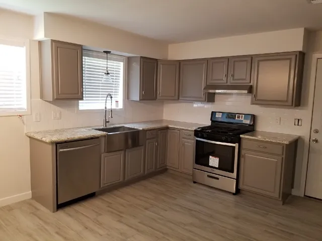 a kitchen with kitchen island granite countertop a sink cabinets and wooden floor