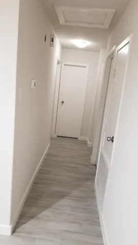 a view of a hallway with wooden floor and entryway