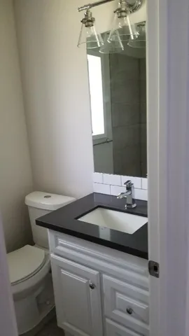 a bathroom with a granite countertop toilet a sink and mirror