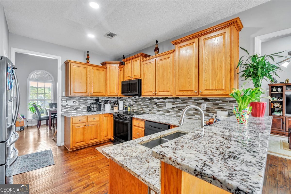 605 Dodds Walk Macon, GA 31220 - Photo 9 of 68 a kitchen with stainless steel appliances granite countertop sink stove and wooden cabinets