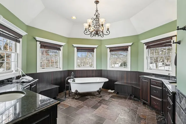 a spacious bathroom with a granite countertop sink a large mirror a bathtub and window