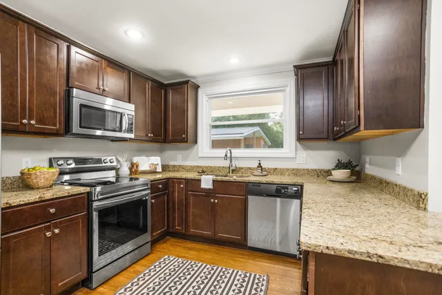a kitchen with stainless steel appliances granite countertop wooden cabinets a stove top oven a sink and dishwasher