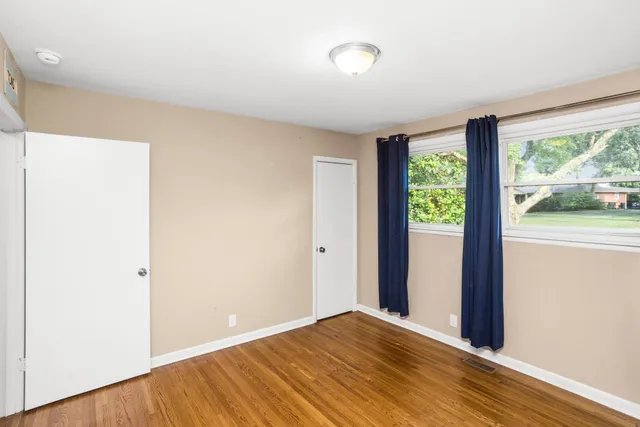 a view of an empty room with wooden floor and a window