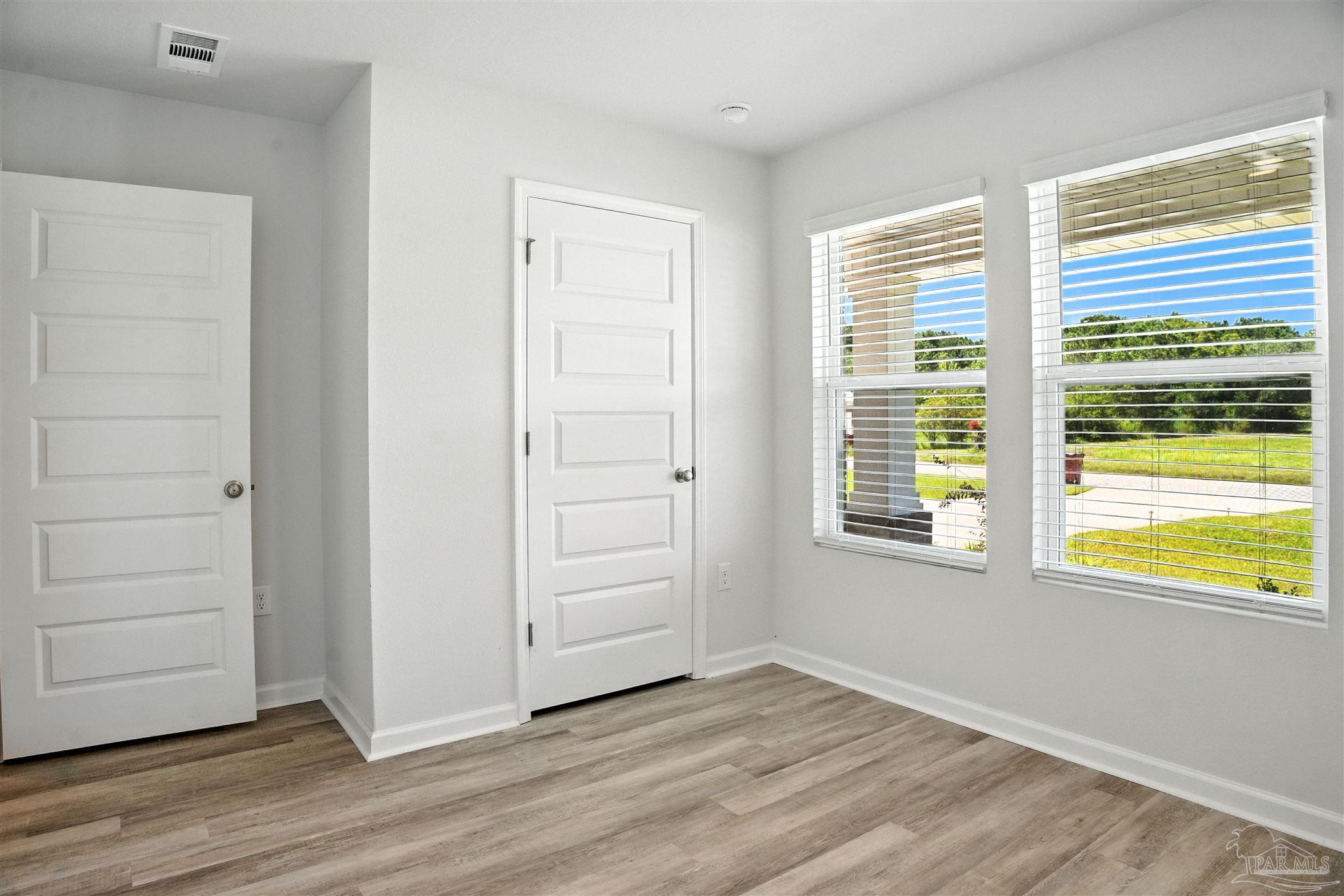 4710 Carl Booker Road Milton, FL 32583 - Photo 15 of 54 an empty room with wooden floor and windows