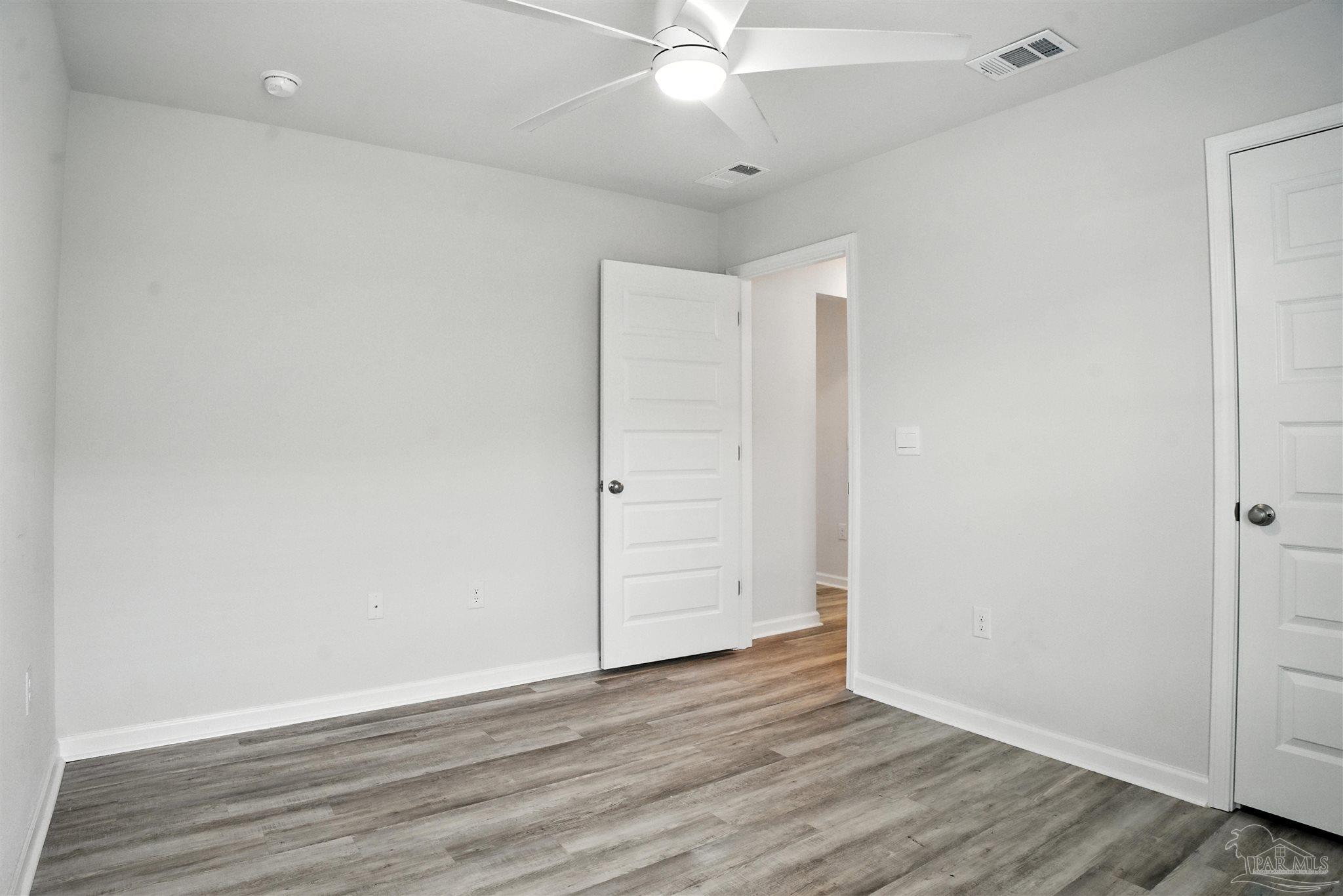 4710 Carl Booker Road Milton, FL 32583 - Photo 32 of 54 an empty room with wooden floor and ceiling fan