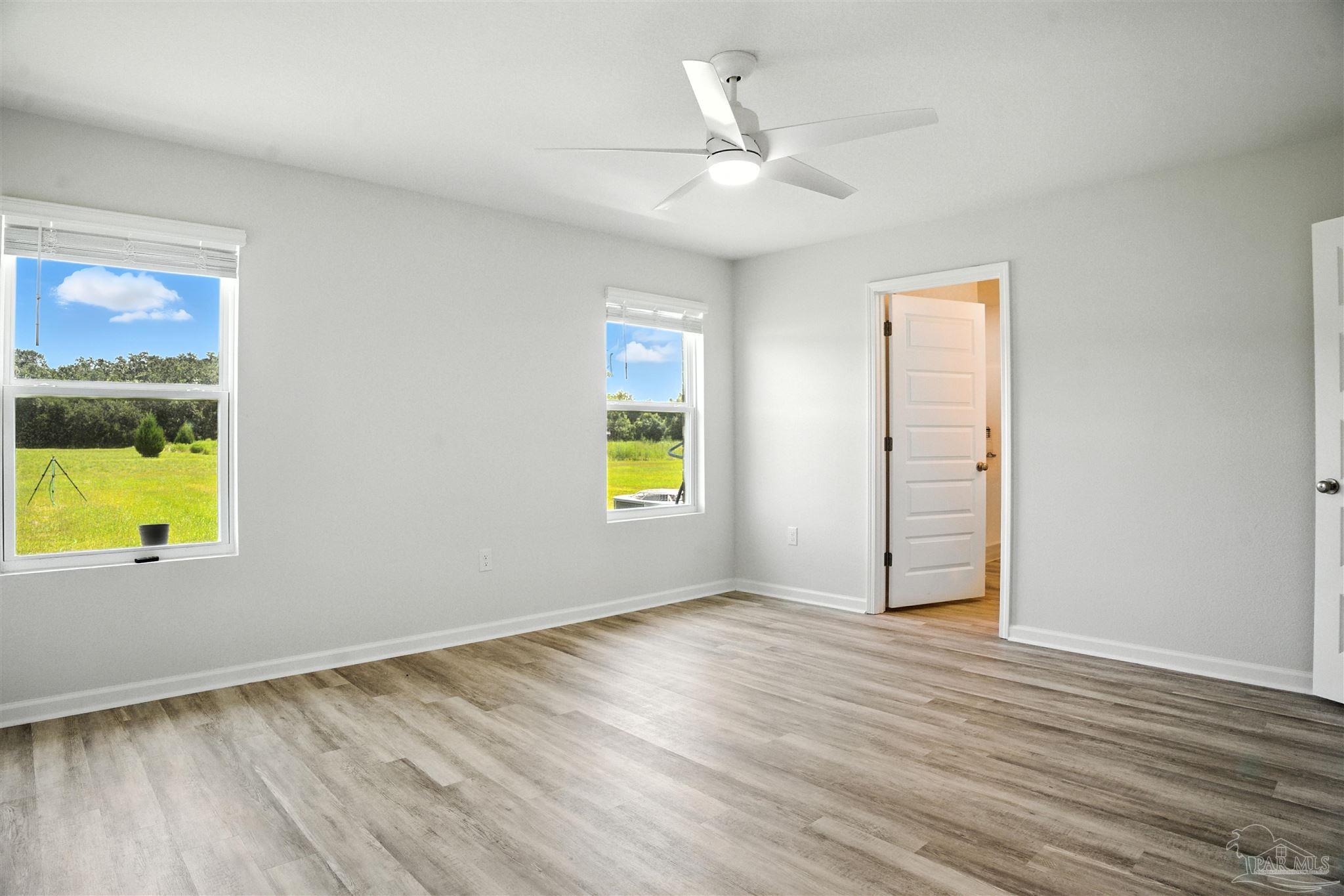 4710 Carl Booker Road Milton, FL 32583 - Photo 38 of 54 an empty room with wooden floor and windows
