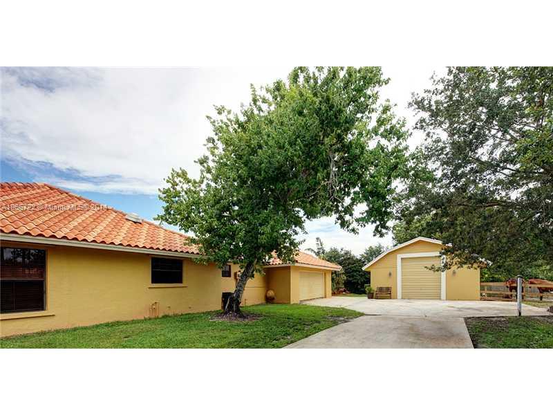 17641 Southwest 70th Place Southwest Ranches, FL 33331 - Photo 17 of 24 a front view of a house with a garden and trees