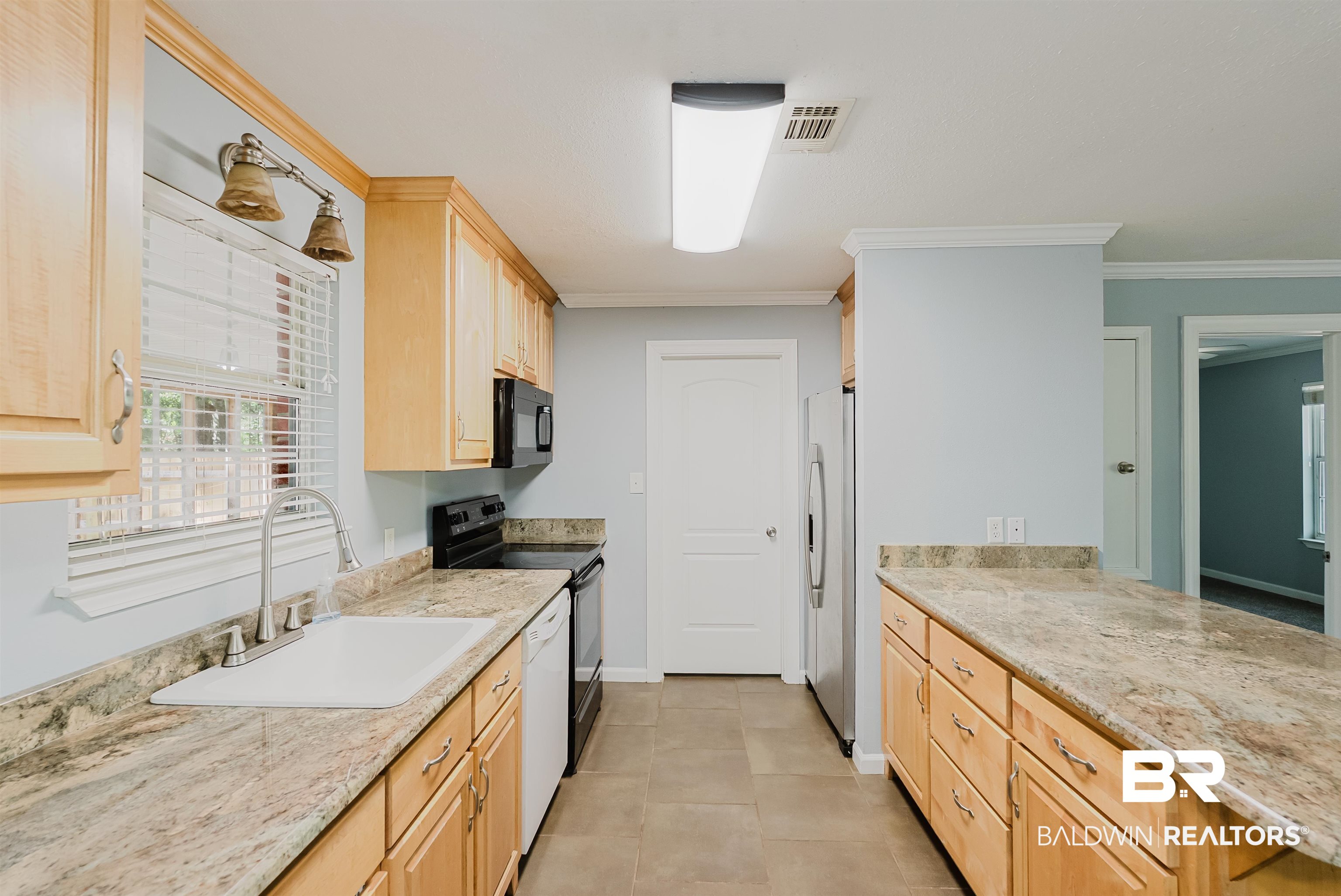 14185 Jackson Lane Foley, AL 36535 - Photo 2 of 16 Kitchen with light brown cabinets, black appliances, light stone countertops, ornamental molding, and light tile patterned flooring
