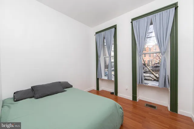 a bedroom with a bed and a large mirror next to a window