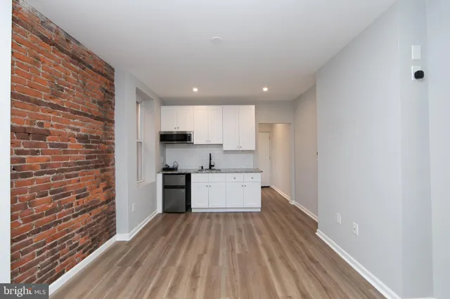 a kitchen with cabinets wooden floor and stainless steel appliances