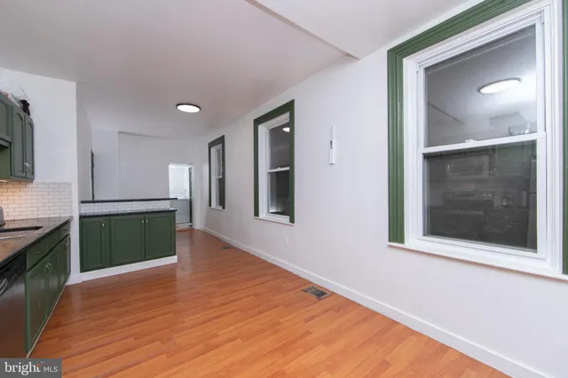 a view of a hallway with wooden floor and a kitchen