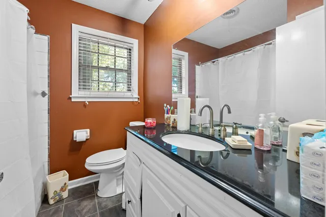 a bathroom with a granite countertop sink mirror vanity and toilet