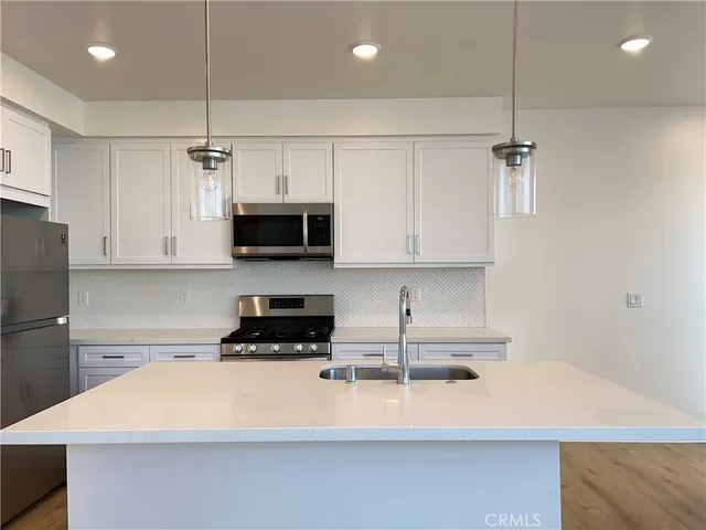 a kitchen with stainless steel appliances granite countertop a sink a stove a microwave and white cabinets