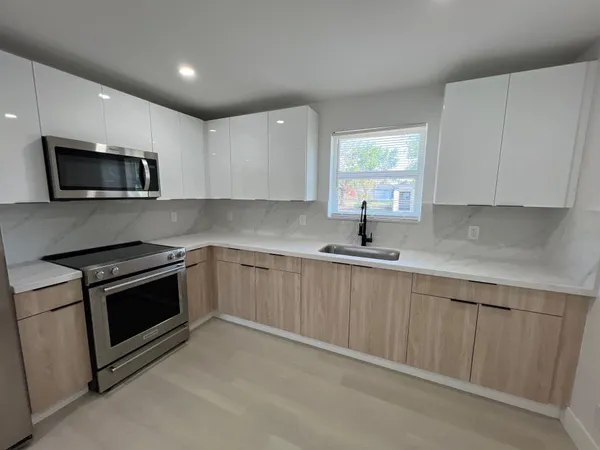 a kitchen with sink a microwave a stove and cabinets
