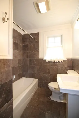 a bathroom with a sink a toilet a mirror and bathtub