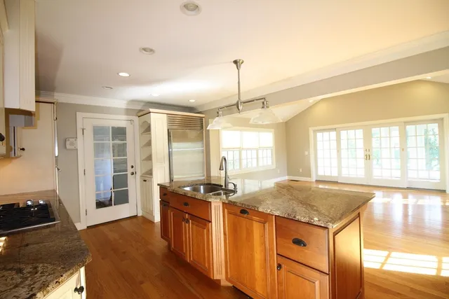 a kitchen with granite countertop a stove a sink a refrigerator and wooden floor
