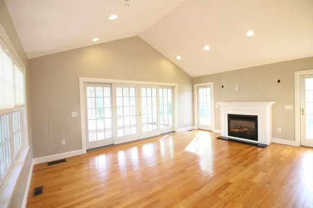an empty room with wooden floor fireplace and windows