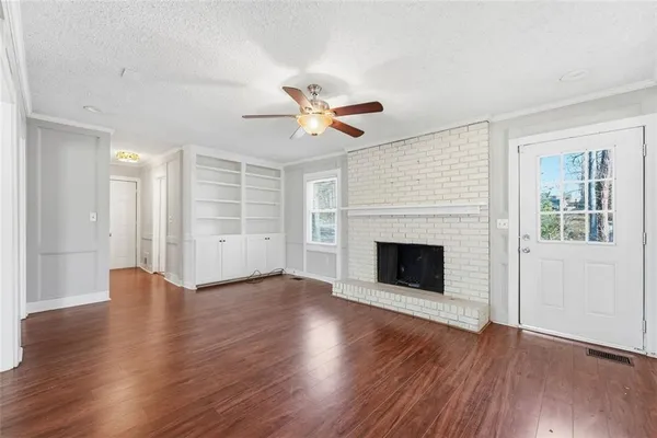 a view of an empty room with wooden floor fireplace and a window