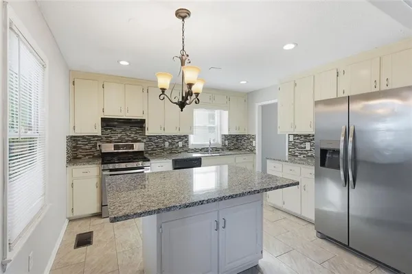 a kitchen with stainless steel appliances granite countertop a refrigerator a sink and a stove