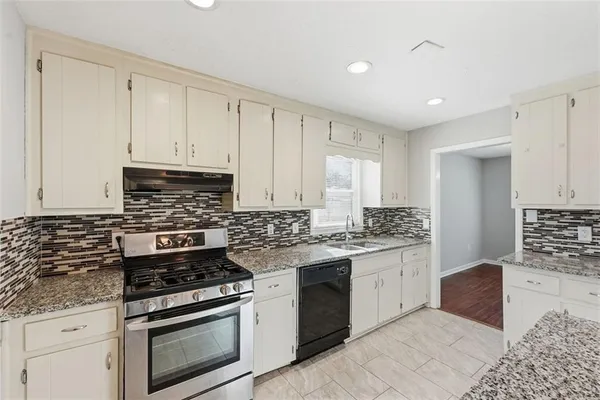 a kitchen with stainless steel appliances granite countertop a stove a sink and a refrigerator