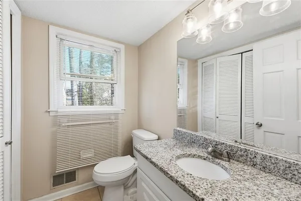 a bathroom with a granite countertop toilet a sink and a mirror