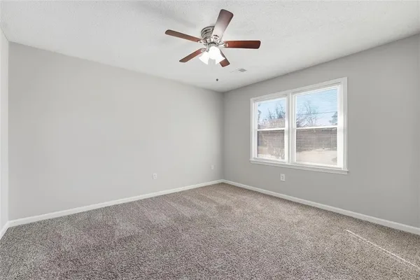 an empty room with window and ceiling fan