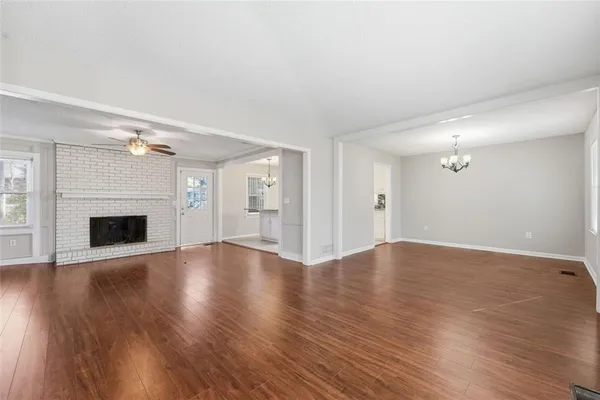 an empty room with wooden floor fireplace and windows