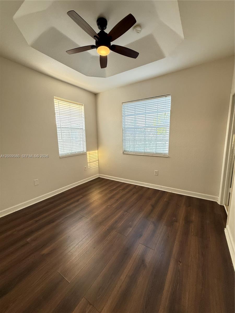 9239 Southwest 227th Street, Unit 1 Cutler Bay, FL 33190 - Photo 19 of 39 an empty room with wooden floor and windows
