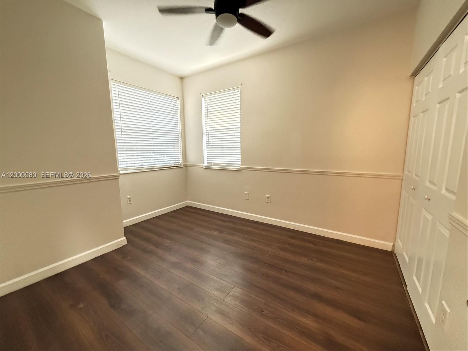 9239 Southwest 227th Street, Unit 1 Cutler Bay, FL 33190 - Photo 25 of 39 an empty room with wooden floor fan and windows