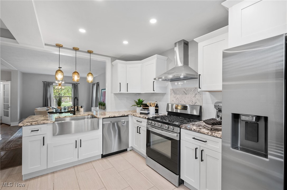 3045 Scarborough Road Cleveland, OH 44118 - Photo 18 of 42 Kitchen with wall chimney range hood, appliances with stainless steel finishes, a sink, a peninsula, and white cabinetry