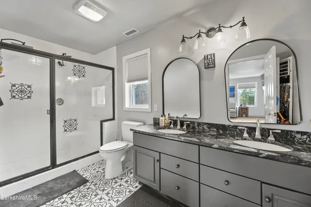 a bathroom with a double vanity sink toilet and shower