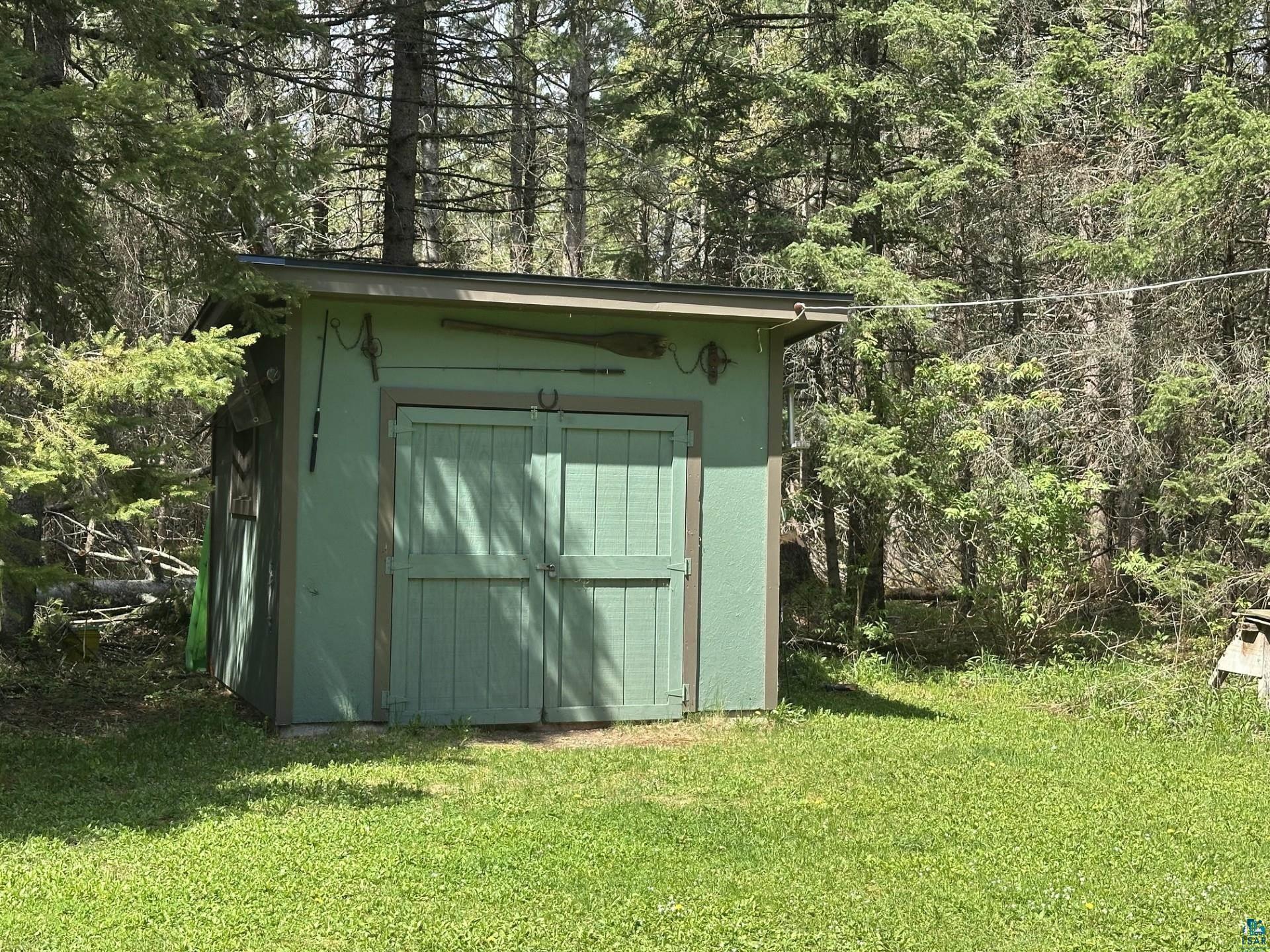 81 Hautaluoma Road Esko, MN 55733 - Photo 42 of 43 Green storage shed with double doors and a dark-colored roof