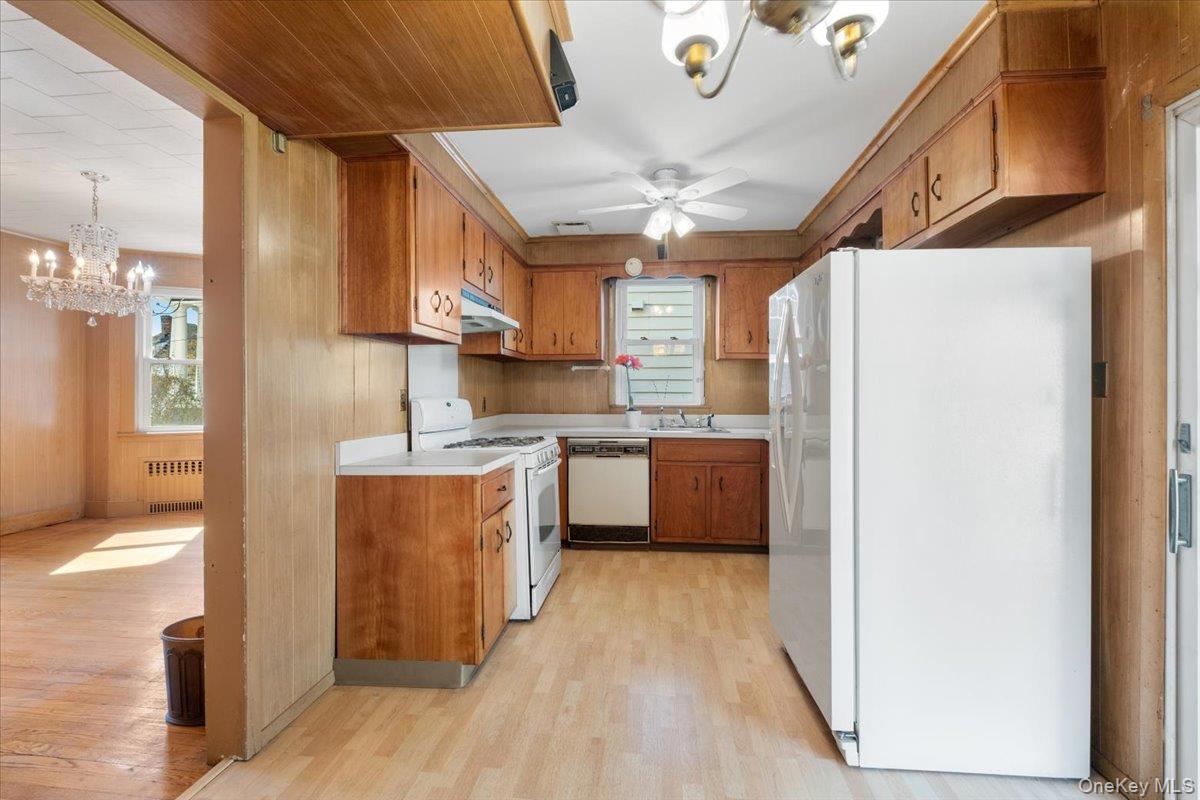 18 Faneuil Place New Rochelle, NY 10801 - Photo 11 of 40 Kitchen featuring ceiling fan, white appliances, light countertops, light wood-style flooring, and wood finish cabinetry. Unknown if dishwasher works.