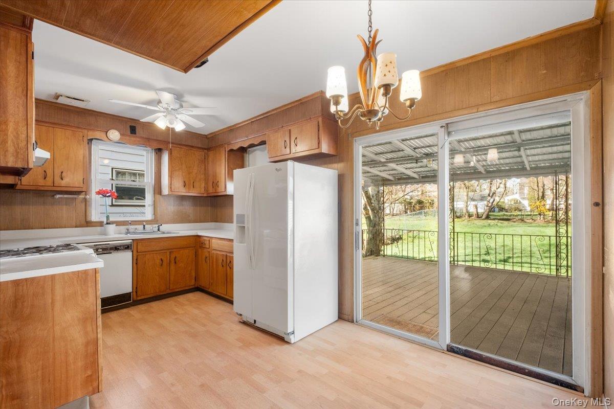 18 Faneuil Place New Rochelle, NY 10801 - Photo 12 of 40 Kitchen featuring white appliances, light countertops, ceiling fan, wood finish cabinets, light wood-type flooring with ample space for table & chairs and sliders to deck and level yard.