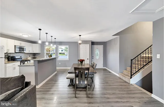 a dining room with kitchen island stainless steel appliances furniture large window and wooden floor