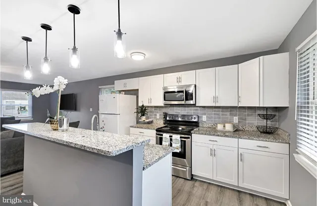 a kitchen with stainless steel appliances kitchen island granite countertop a sink a stove and cabinets