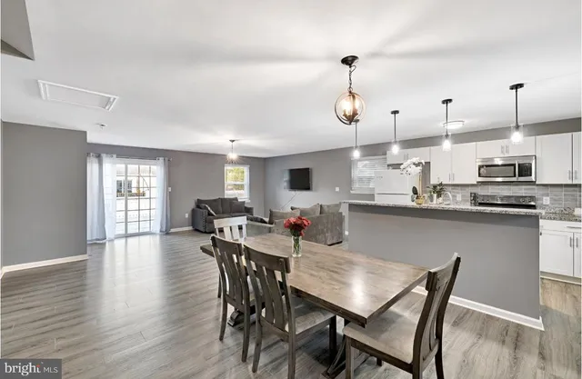 a kitchen with stainless steel appliances kitchen island granite countertop a dining table chairs and granite counter tops