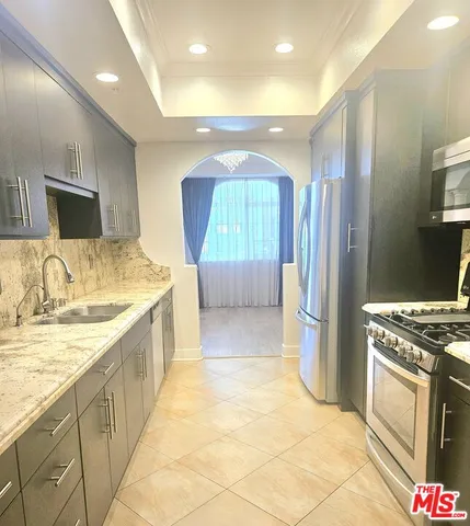 a kitchen with stainless steel appliances granite countertop a refrigerator a stove and a sink