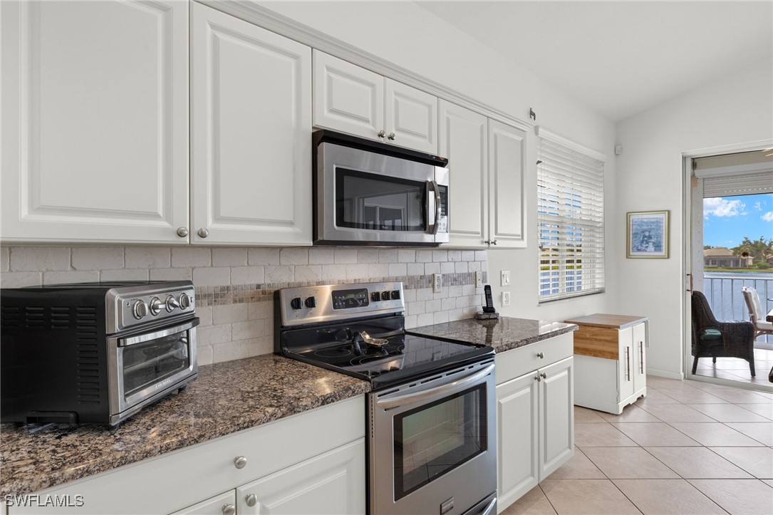 16253 Coco Hammock Way, Unit 201 Fort Myers, FL 33908 - Photo 12 of 34 a kitchen with granite countertop a stove top oven microwave and cabinets