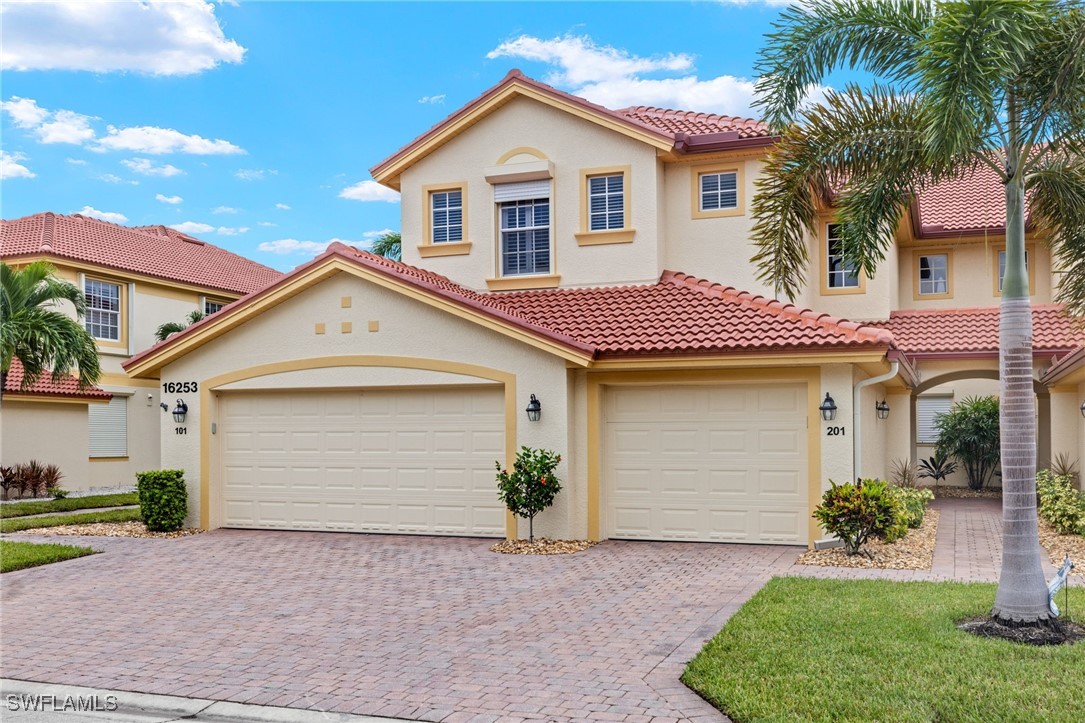 16253 Coco Hammock Way, Unit 201 Fort Myers, FL 33908 - Photo 2 of 34 a front view of a house with a yard and garage