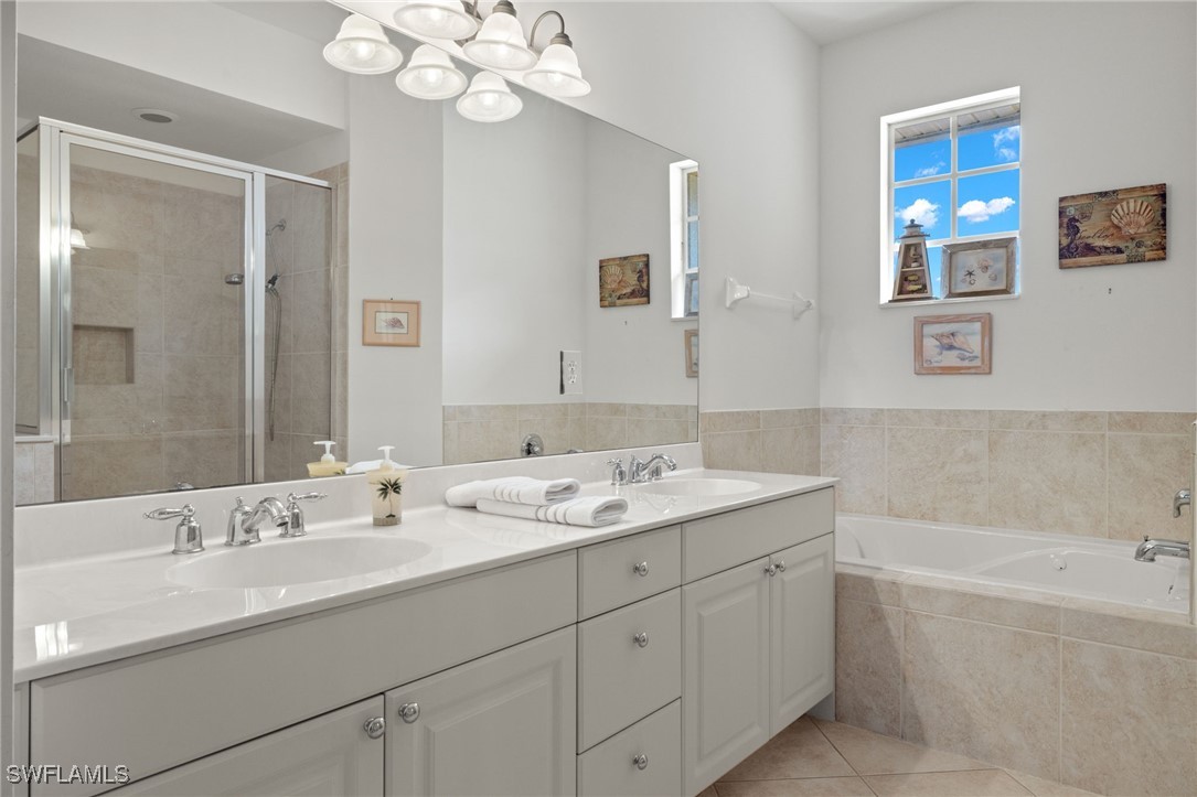 16253 Coco Hammock Way, Unit 201 Fort Myers, FL 33908 - Photo 23 of 34 a bathroom with a granite countertop sink a large mirror a shower and a bathtub