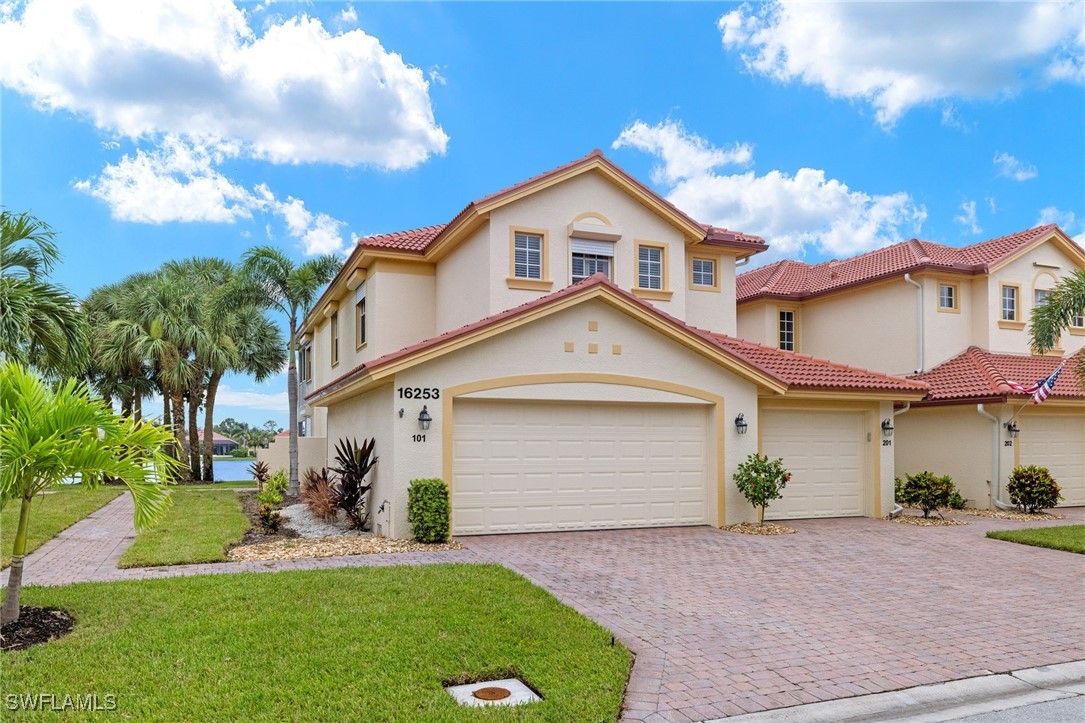 16253 Coco Hammock Way, Unit 201 Fort Myers, FL 33908 - Photo 26 of 34 a front view of a house with a yard and garage