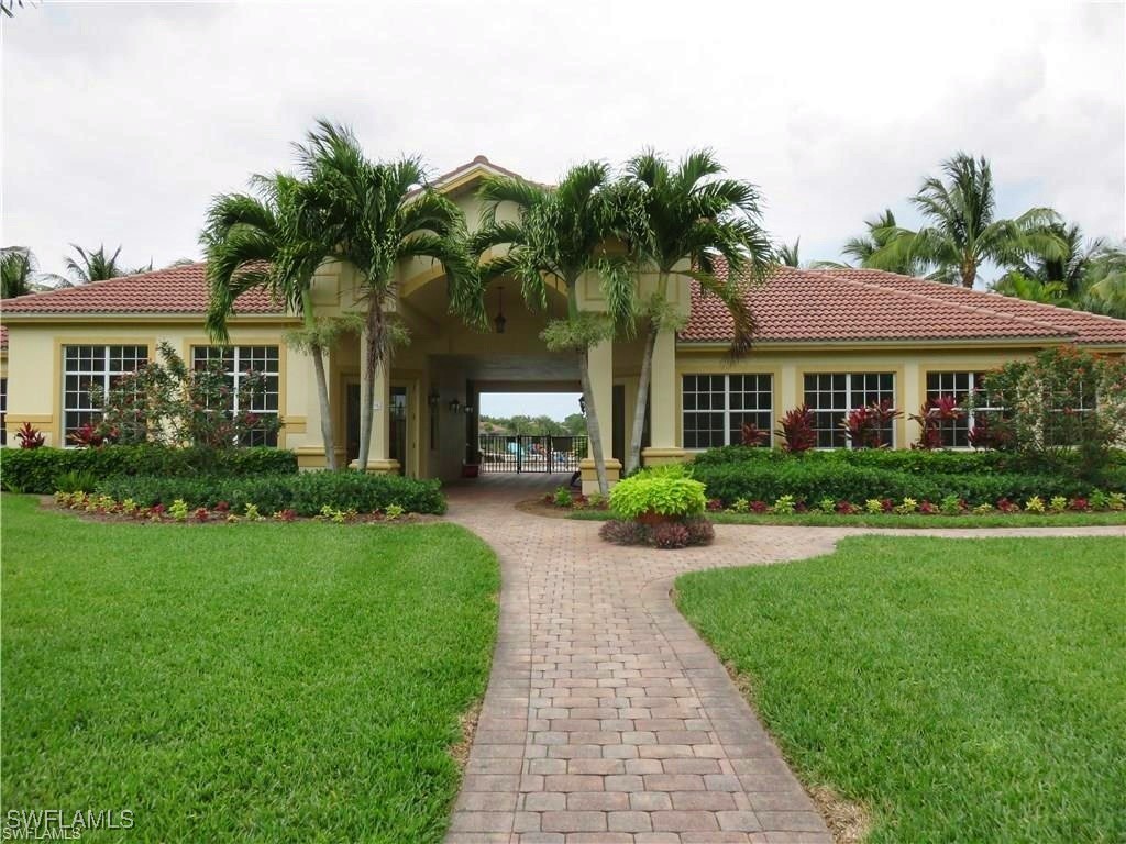 16253 Coco Hammock Way, Unit 201 Fort Myers, FL 33908 - Photo 33 of 34 a front view of a house with a yard and potted plants