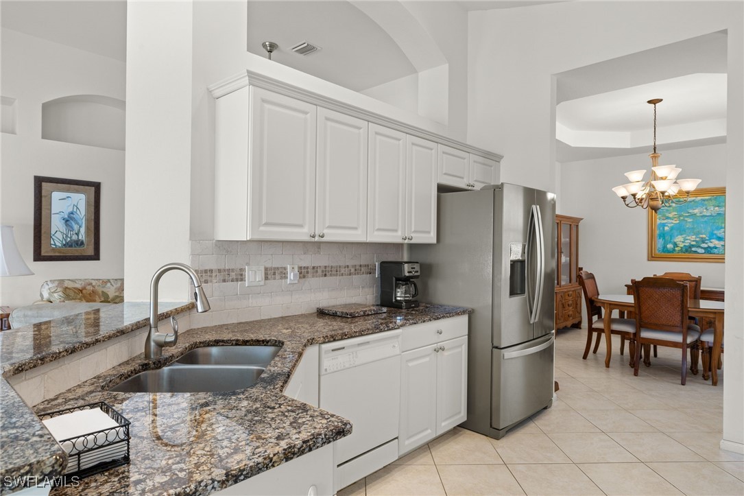 16253 Coco Hammock Way, Unit 201 Fort Myers, FL 33908 - Photo 4 of 34 a kitchen with a refrigerator sink and white cabinets