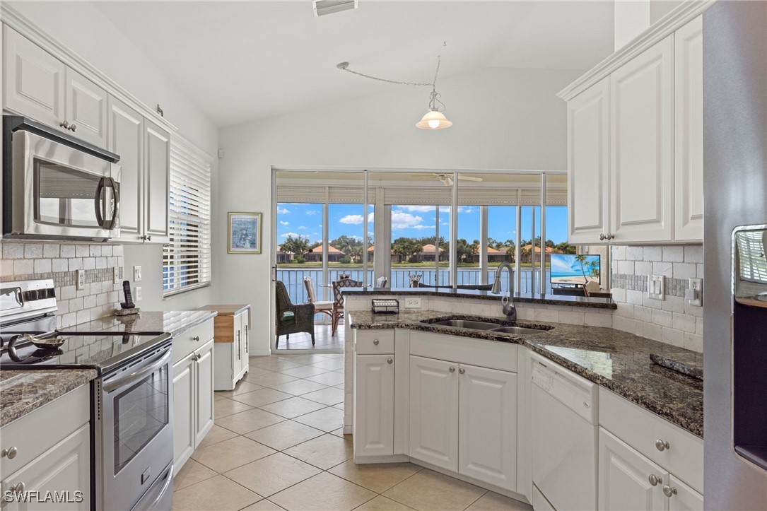 16253 Coco Hammock Way, Unit 201 Fort Myers, FL 33908 - Photo 10 of 34 a kitchen with stainless steel appliances granite countertop a stove sink and cabinets