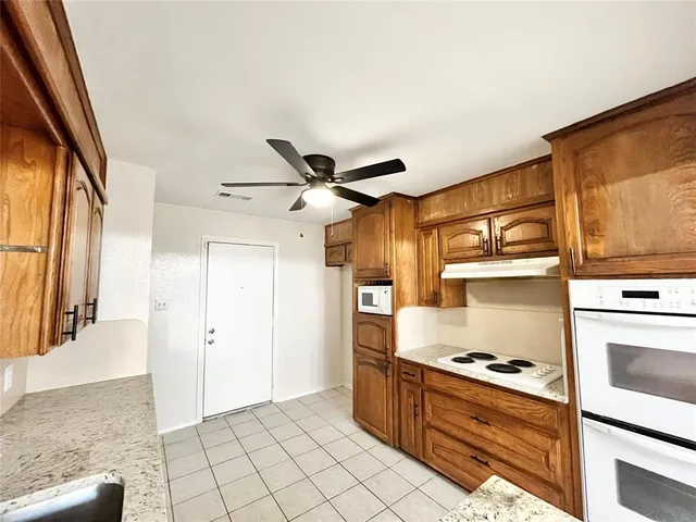 a kitchen with stainless steel appliances granite countertop a refrigerator a stove and a sink with wooden cabinets