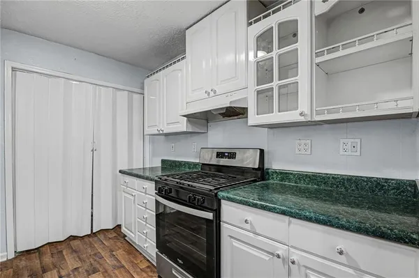 a kitchen with granite countertop white cabinets and stainless steel appliances