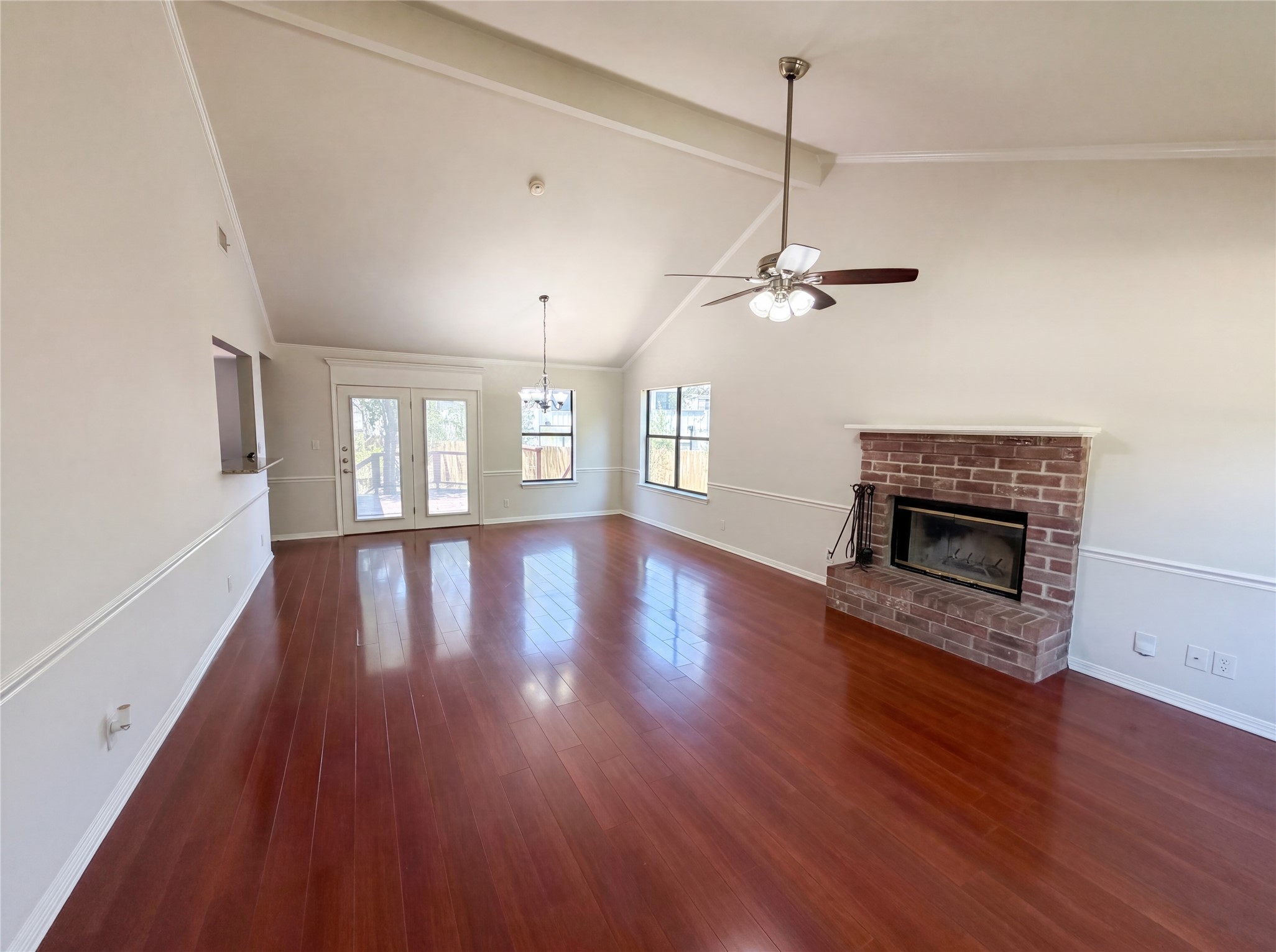 1111 North Riviera Circle Cedar Park, TX 78613 - Photo 3 of 17 Spacious living area featuring high vaulted ceilings, polished wood-finish flooring, a brick fireplace with mantel, and double glass-panel doors