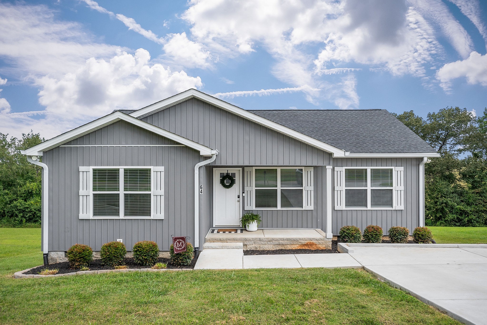 a front view of a house with a yard and potted plants