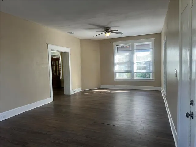 an empty room with wooden floor chandelier and windows